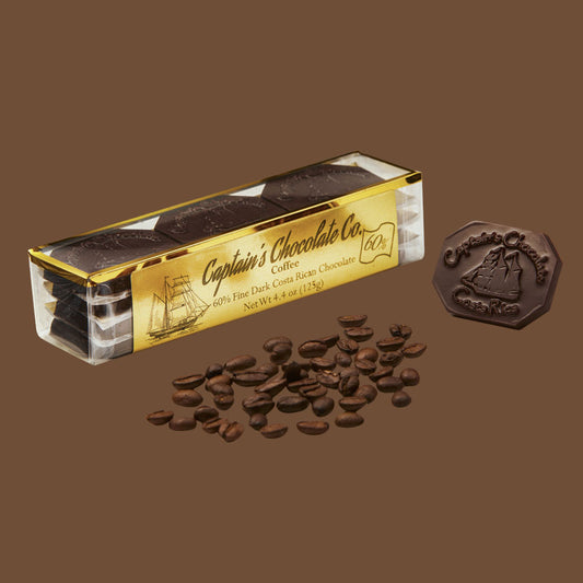 small rectangular translucent box set of chocolate medallions posing with coffee beans and a loose medallion on a brown background